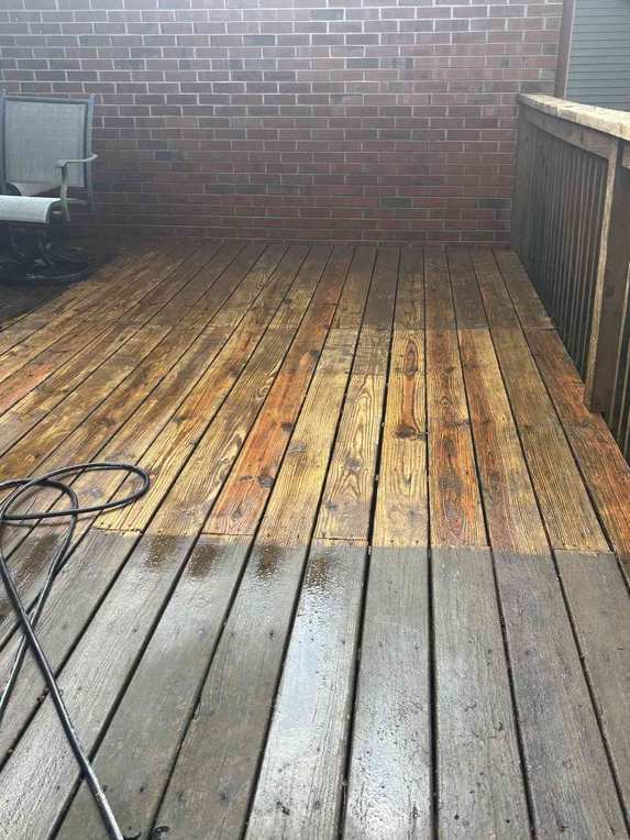 A real Moore Lawncare pressure washing job showing a dramatic clean-versus-dirty line on a wood deck